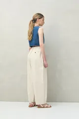 Pantalón color crema de corte ancho, con cintura alta y pinzas delanteras.