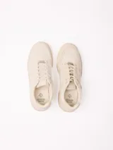 Championes de plataforma baja de color beige, con cordones tono sobre tono y detalle de placa metálica en los cordones.