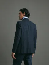 Saco de vestir azul oscuro con textura sutil, corte entallado, cierre frontal de un botón y solapas clásicas.