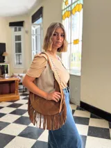 Cartera bandolera de cuero color camel con flecos largos en la parte inferior.