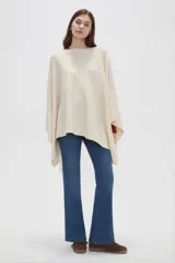 Poncho crudo de tejido de punto con diseño holgado y sin mangas.