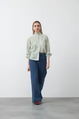 Camisa de viscosa con estampado de lunares, cuello alto con volados y cierre frontal de botones. Presenta un diseño de silueta suelta con frunces que aportan volumen y mangas largas con puños ajustados.