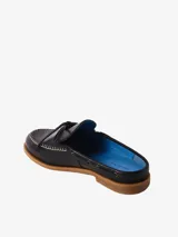 Zueco de cuero negro estilo náutico, con costuras expuestas en contraste, detalle de lazo en el empeine y suela de goma.