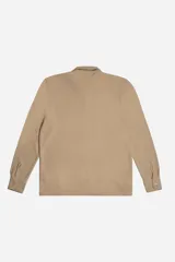 Camisa de manga larga confeccionada en tejido tipo waffle, color beige. Presenta cuello clásico, botonadura frontal y logo de la marca bordado discretamente en el pecho.