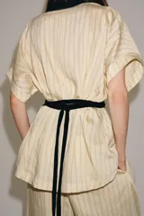Kimono Zara Woman Collection de manga corta y cuello en V, confeccionado en tejido color crudo con sutiles rayas verticales. Presenta aplicaciones de terciopelo negro a contraste en la solapa y un fajín ancho integrado en la cintura.