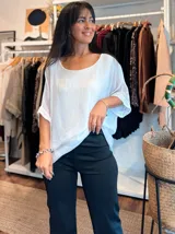 Blusa de seda blanca con cuello redondo y mangas cortas amplias de corte holgado. Presenta una textura sutilmente arrugada y un diseño minimalista.