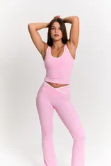 Conjunto deportivo compuesto por top de tirantes anchos con ribete blanco y pantalón tipo flare de tiro alto con cintura cruzada en V y detalle de ribete blanco.