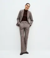 Pantalón flare de tiro medio en punto roma con estampado de cuadros en tonos marrones y grises. Presenta cintura estructurada con un detalle de hebilla metálica lateral y diseño acampanado desde la rodilla.