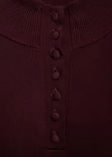 Jersey de punto fino color bordó con cuello perkins y cierre frontal parcial de botones. Presenta diseño recto, manga larga y terminaciones elásticas en canalé.