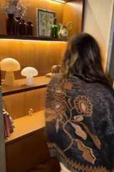 Saco tipo cardigan de tejido jacquard color azul, con cierre frontal de aluminio y cuello alto. Presenta un diseño estampado de flores en la espalda y detalles geométricos en los bordes.