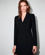 Vestido tipo blazer de corte corto y color negro, con solapas de muesca, doble botonadura frontal y bolsillos de ojal con solapa.