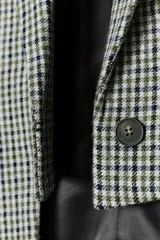 Blazer Zara de corte asimétrico confeccionado en tejido con lana. Presenta un diseño de cuadros, cuello con solapas de muesca, manga larga y cierre frontal cruzado con botones. El bajo es asimétrico con una abertura pronunciada en la espalda y cuenta con forro interior.