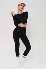 Conjunto deportivo compuesto por un top de manga larga con cuello redondo y calzas de tiro alto, ambos en color negro con detalles de textura en tejido seamless.
