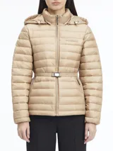 Campera color beige de nailon reciclado, con cuello alto, capucha con cordón ajustable, cierre de cremallera frontal, bolsillos laterales con cremallera, cinturón con hebilla metálica y logo de Calvin Klein en el pecho.