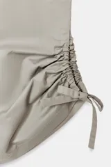 Pantalón tipo culotte de tiro medio con cintura elástica y bolsillos laterales ocultos. Presenta un diseño de pernera ancha con aberturas laterales en el bajo, ajustables mediante cordones con frunces.