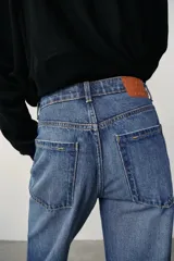 Jeans de tiro alto, pernera recta y larga, estilo clásico con cinco bolsillos, cierre frontal con cremallera y botón metálico.