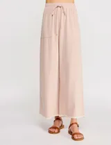 Pantalón palazzo de lino color beige, de tiro alto y silueta suelta, con cintura elastizada y cordón de ajuste. Cuenta con detalles de ribetes bordados festoneados en contraste en los bolsillos y en el ruedo.