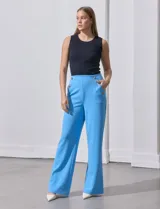 Pantalón naranja de crepe elastizado, corte recto, con bolsillos delanteros y apliques de botones metálicos.