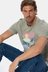 Remera celeste melange de manga corta con cuello redondo y estampa veraniega al frente con motivo de playa y la inscripción "Legacy Sun Coast".