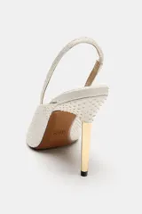 Zapato de tacón destalonado color blanco con textura en relieve efecto piel de serpiente, punta fina y tacón alto metalizado en tono dorado.