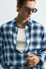 Camisa de corte regular fit confeccionada en tejido fluido de algodón y viscosa. Presenta un diseño de cuadros, cuello solapa, manga larga con puños abotonados, bolsillo en el pecho y cierre frontal con botones.