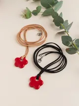 Collar de tiento de cuero con dije de porcelana en forma de flor esmaltada en rojo.