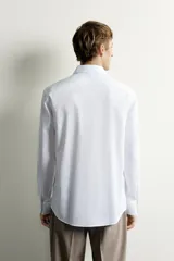 Camisa de corte slim fit, color celeste, con cuello italiano y manga larga con puños abotonados. Presenta un tejido con textura y cierre frontal de botones.