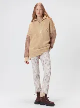 Pullover de tejido acanalado grueso con cuello alto y cierre frontal parcial. Presenta un diseño de bloques de color con cuerpo en tono beige y mangas en contraste con rayas verticales en color bordó. Incluye un detalle bordado en el pecho.