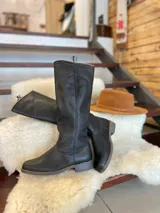 Botas altas de montar de cuero color marrón, con diseño plano y suela de goma.