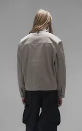 Chaqueta de corte regular crop confeccionada en microfibra pesada levemente elastizada. Presenta cuello volcado, cierre frontal con broches snap a tono y bolsillos delanteros con solapa.