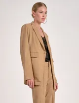 Blazer de mujer color beige, confeccionado en material similar a la gamuza, con solapas anchas, un botón forrado en la parte frontal y bolsillos de ojal.