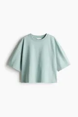 Remera color verde agua, de corte cuadrado y holgado, con cuello redondo y mangas cortas anchas.