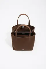 Bolso tipo tote de Bimba y Lola en color marrón, confeccionado en gabardina con detalles en piel. Cuenta con doble asa de mano, asa bandolera regulable, cierre con botón de presión y logo metálico aplicado en el frente.