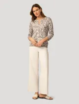 Cardigan de punto con estampado de mariposas en tonos grises y blancos. Presenta cuello redondo, cierre frontal con botones y mangas tres cuartos con puños acanalados.