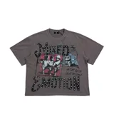 Remera de algodón color gris con efecto lavado, de corte oversize y manga corta. Presenta un estampado gráfico frontal con querubines, texto con apliques de tachas y detalles de estilo urbano.