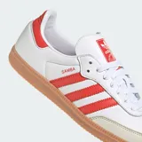 Championes Adidas modelo Samba OG, fabricados en cuero blanco con las icónicas tres tiras y detalles en rojo solar, puntera de nobuk gris claro y suela de goma marrón.