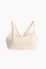 Top deportivo de soporte medio color beige claro con escote redondo y doble tirante en los hombros.