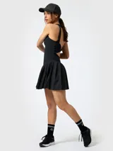 Vestido corto deportivo negro con falda plisada y short interior integrado, de tirantes anchos y cuello redondo.