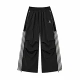 Pantalón deportivo baggy negro, confeccionado en tela waterproof resistente al agua. Cuenta con cintura elástica con regulador, bolsillos con cierre, cierres completos en los laterales y bandas de tres rayas blancas.