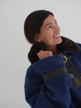 Buzo color crudo con cuello de piel sintética color crema, abertura parcial con cierre de cuero marrón y hebilla dorada, puños con ajuste de cuero marrón y bolsillos laterales.