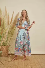 Vestido largo estampado con motivos florales y de animales en tonos azules, verdes, rosas y naranjas. Presenta mangas abullonadas y un corte en la cintura con un patrón de animal print.