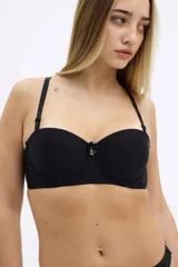 Soutien strapless negro con copas preformadas, aro y breteles removibles. Presenta un pequeño lazo y un dije con forma de triángulo en el centro.