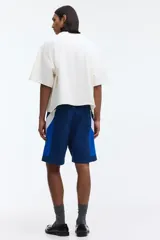 Short de baño y deportivo confeccionado en nylon, de corte holgado. Presenta un diseño de bloques de color en tonos azul, azul marino y blanco. Cuenta con cintura elástica con cordón ajustable blanco, bolsillos laterales y aberturas en los costados del ruedo. Incluye suspensor interno de malla.