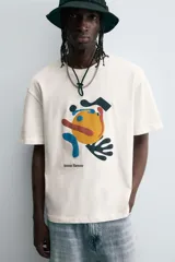 Camiseta de manga corta y cuello redondo, color blanco hueso, con un estampado abstracto multicolor en el pecho que incluye texto en la parte inferior.