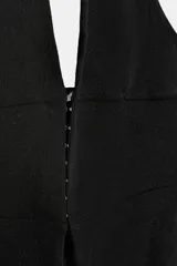 Top entallado color negro de cuello halter, con escote en V pronunciado, espalda descubierta y cierre frontal con ganchos metálicos.