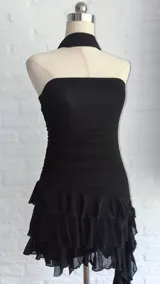 Vestido corto negro de estilo strapless con ajuste drapeado en el torso y falda con volados en capas. Incluye una cinta negra a modo de gargantilla integrada al diseño.