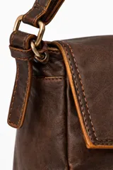 Cartera tipo baguette de cuero, color marrón oscuro, con solapa frontal y correa de hombro ajustable.