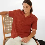 Camisa de manga corta color ladrillo con tejido calado, cuello clásico y cierre frontal con botones.