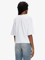 Camiseta blanca de algodón orgánico con corte oversize y forma cuadrada. Presenta un logotipo moderno con efecto 'peekaboo' en el pecho, donde un parche de la 'D' ovalada cortada a láser deja ver la piel.