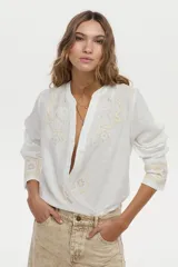 Camisa blanca de lino con cuello mao, manga larga y delicados bordados en tono tostado en el pecho y los puños.